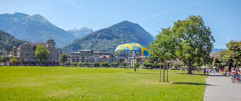 Paraglider landing in park in Interlaken Switzerland in summer during virtual walks