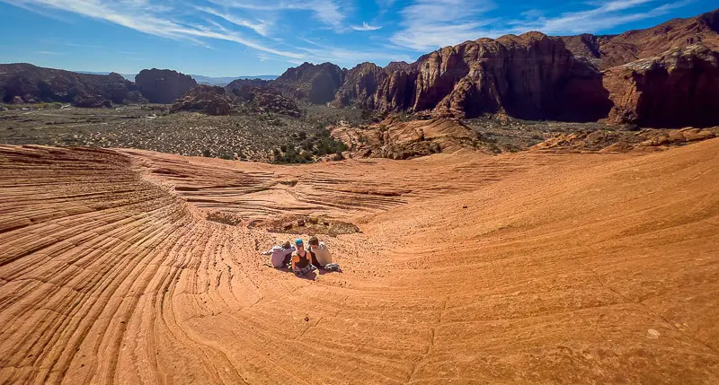 Family sitting on the Red Rocks of Snow Canyon State park after filming virtual walking tours