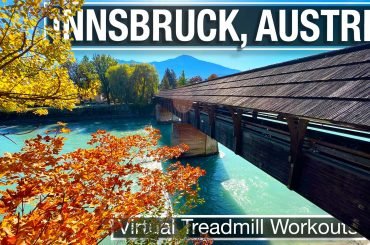 The Hans-Psenner-Steg covered wooden bridge over the Inn river in Innsbruck Austria with fall foliage and blue water