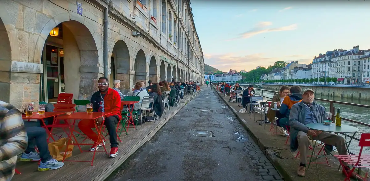 People in an outdoor cafe along the Doubs River in Besançon, France during our walk where city walks live