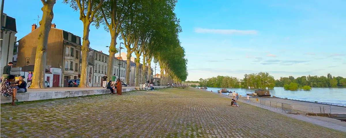 River bank in evening by Loire in Orleans with trees and people socializing during virtual tour